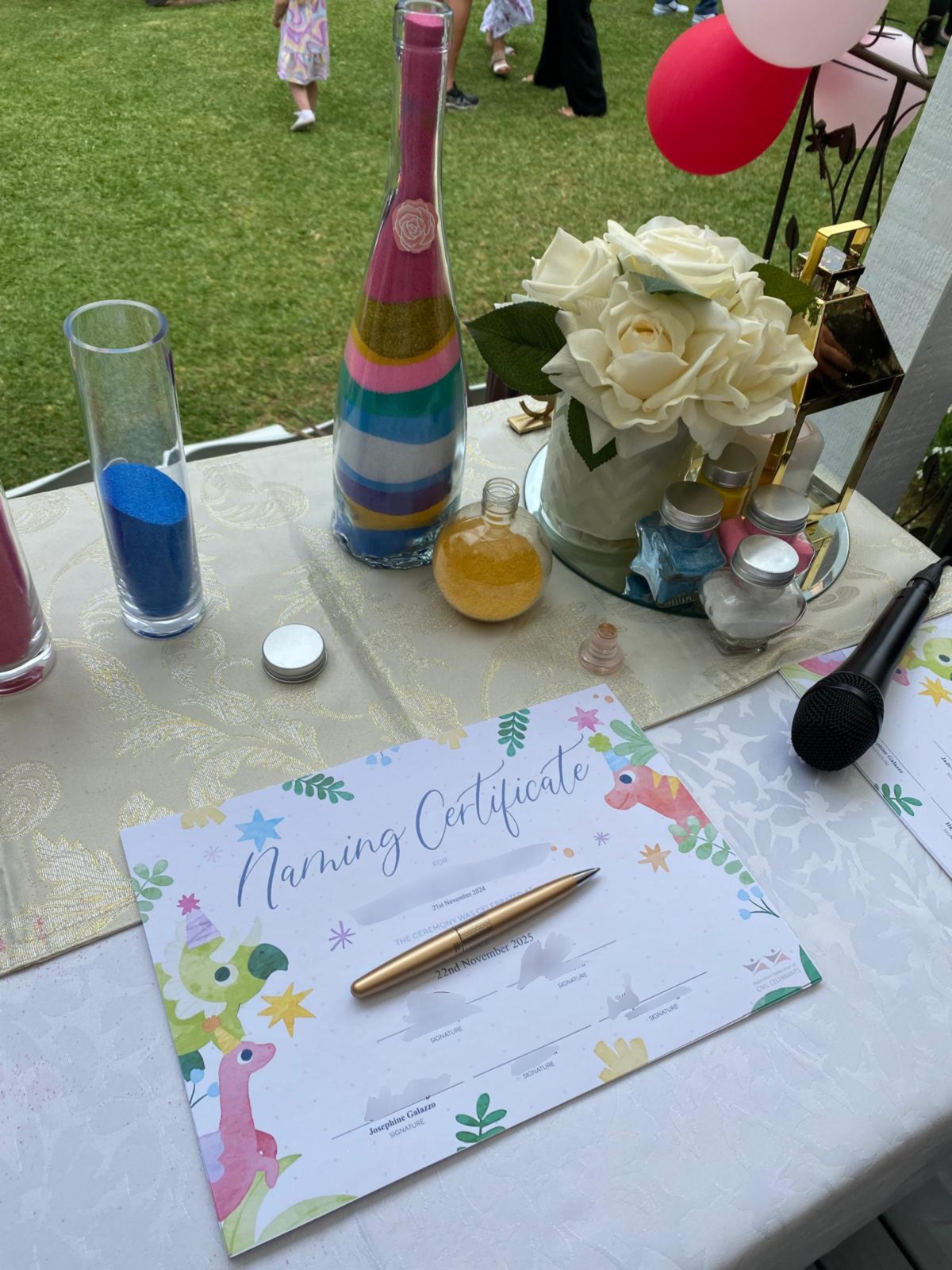 A naming ceremony table set with coloured sand for the sand ceremony, flowers and the naming certificate
